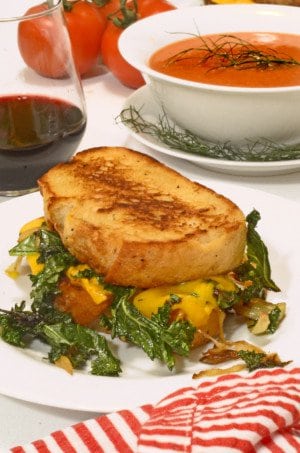 a sandwich on a plate with a glass of wine and soup