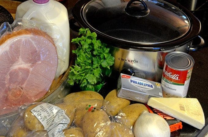 A crockpot with ingredients for scalloped potatoes and ham