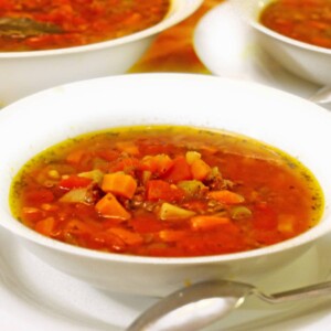 White bowl of ground beef soup with a spoon.