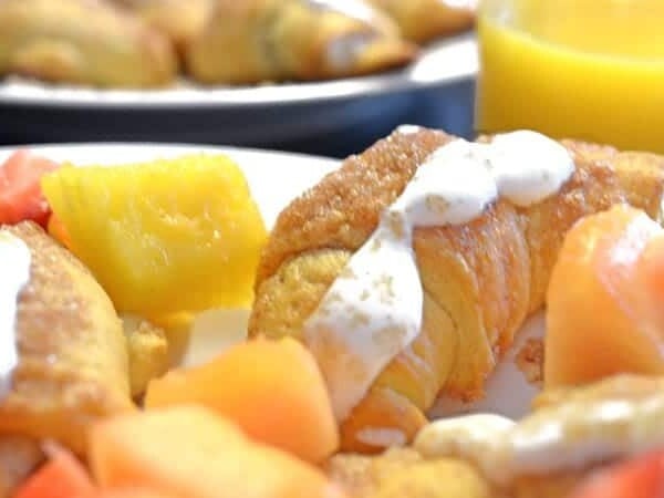 A plate of food with a croissant and fruit