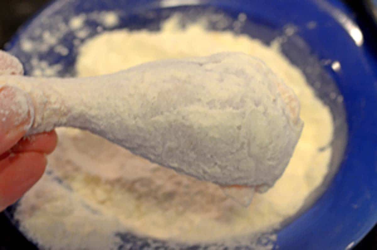 Dredging chiciken in flour.