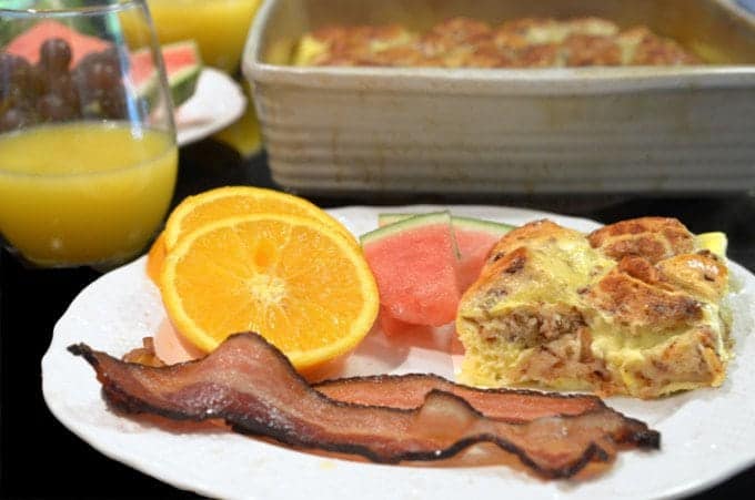 A plate of food with a slice of orange, and bacon