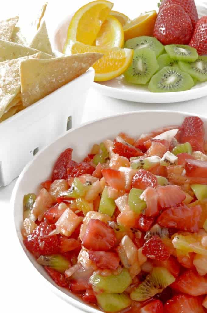 A closeup of a salsa bowl with kiwi and chips