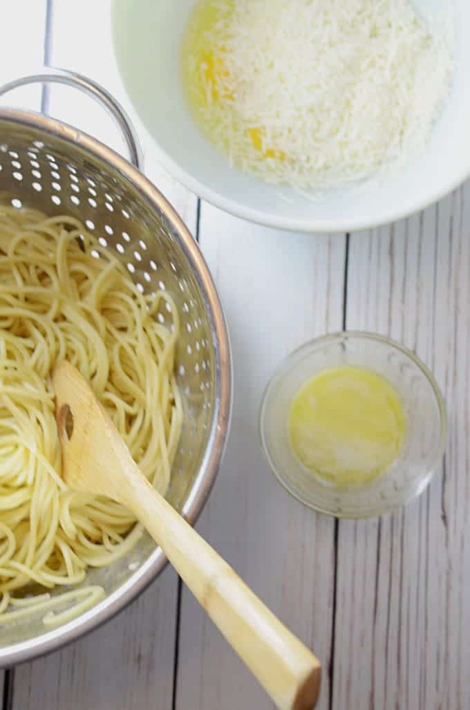 A bowl of pasta sits on top of a wooden table, with Spaghetti and Carbonara
