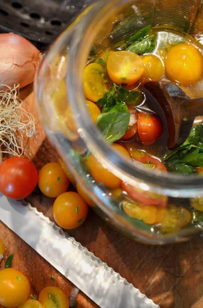 A jar of tomatoes marinating with basil