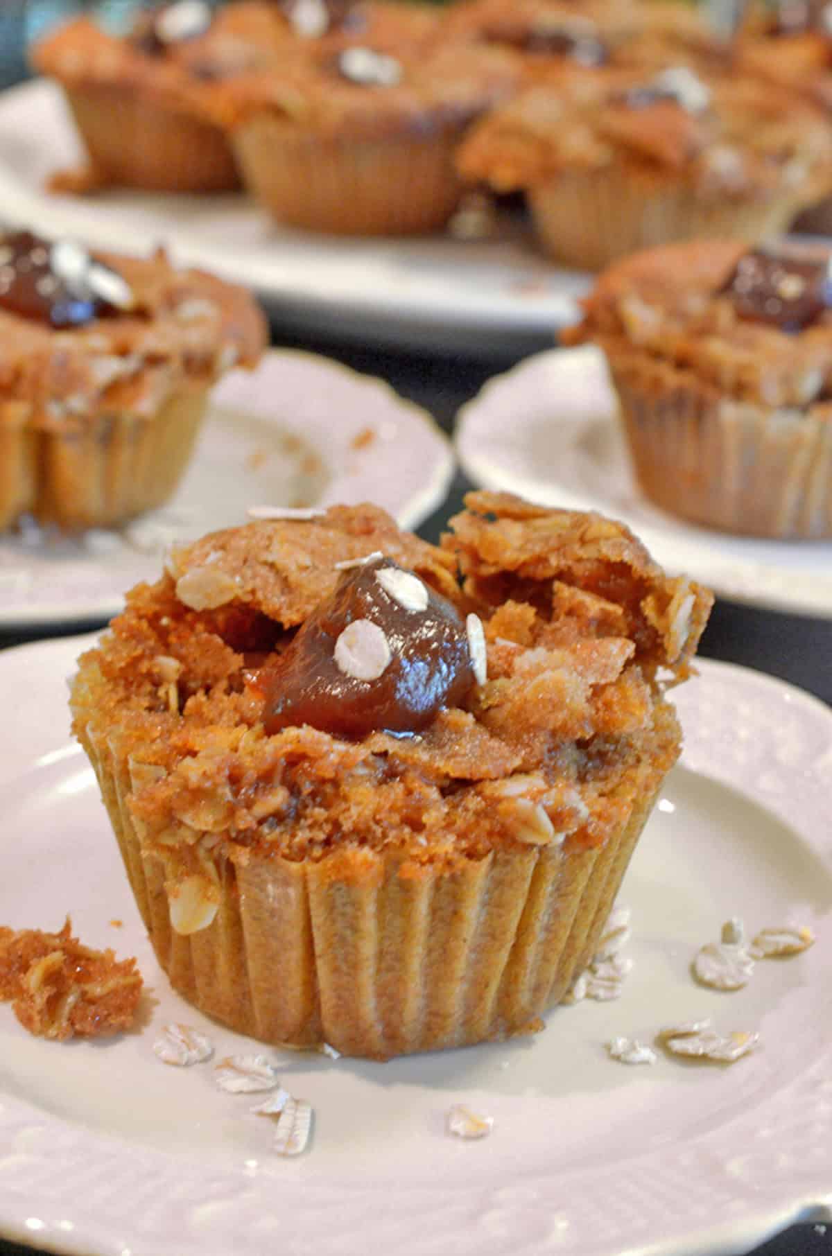 An apple butter muffin with oatmeal streusel, on a white plate.