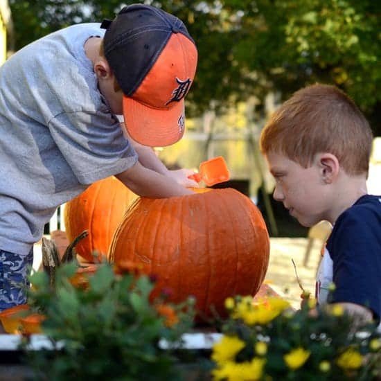 Two young boys carving a pumpkin