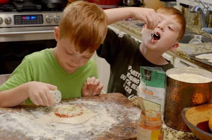 A little boy sitting at a table eating food, with Calzone and Dough