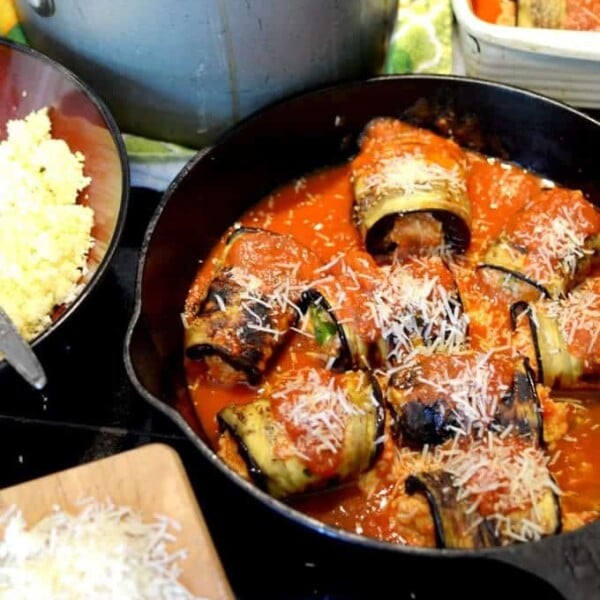 A skillet with rolled eggplant and tomato sauce