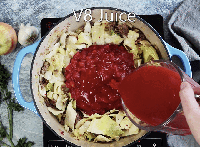 V8 juice being added to pot of cabbage and tomato