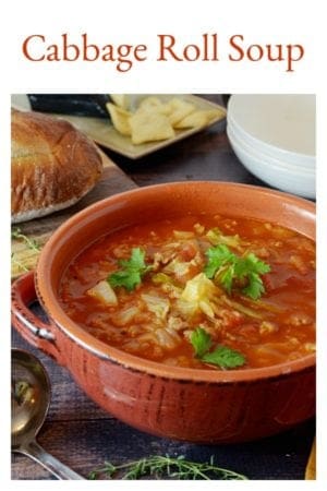 Bowl of cabbage soup on table with baguette on wood