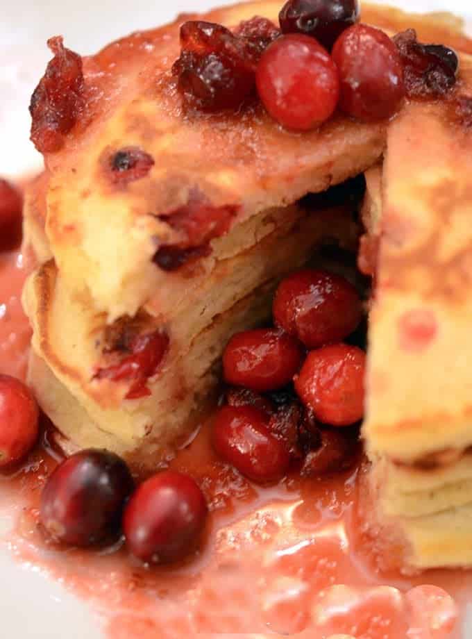 A close-up of a stack of pancakes with cranberries