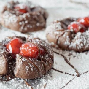 Three chocolarte cookies with cherries on top