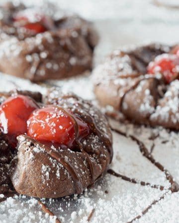 Three chocolarte cookies with cherries on top