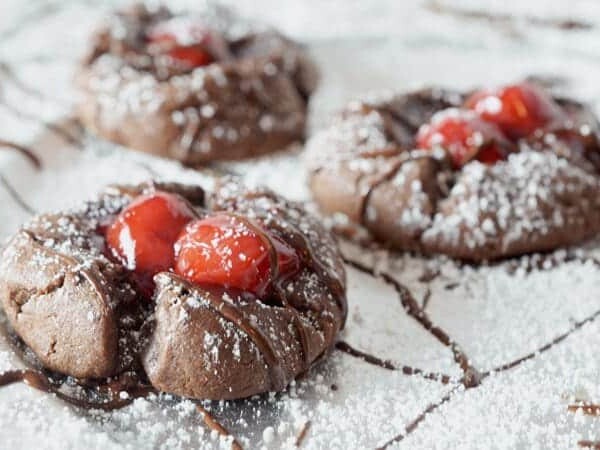 Three chocolarte cookies with cherries on top