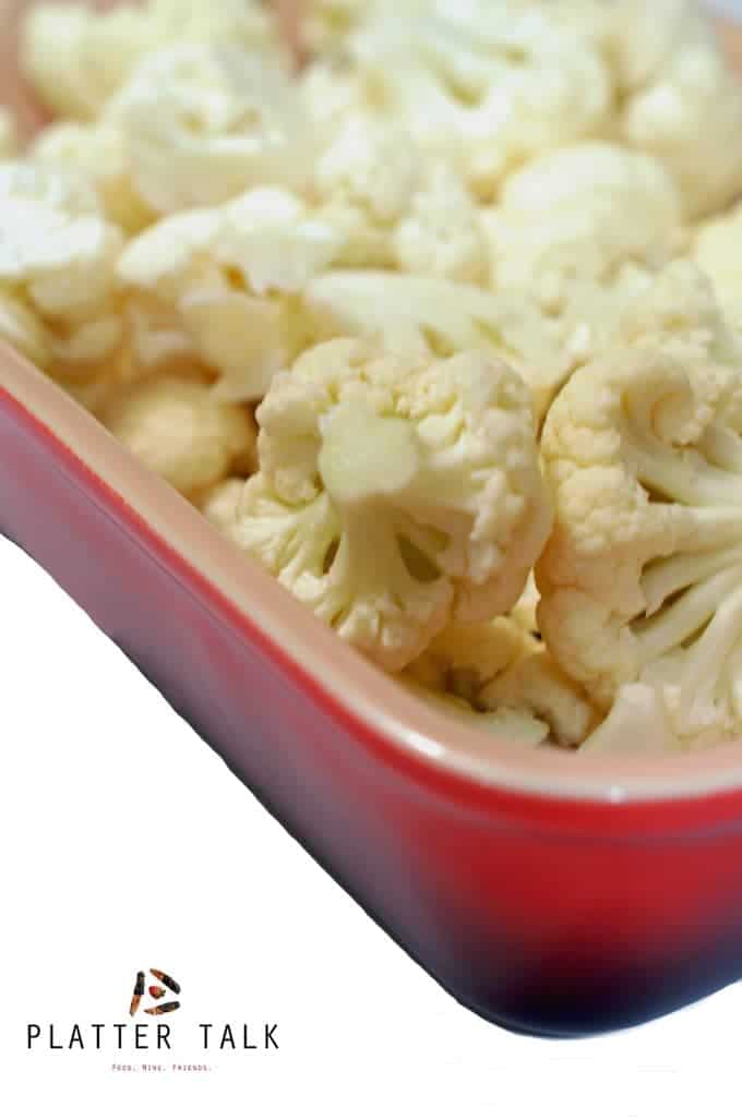 Raw cauliflower pieces in baking dish