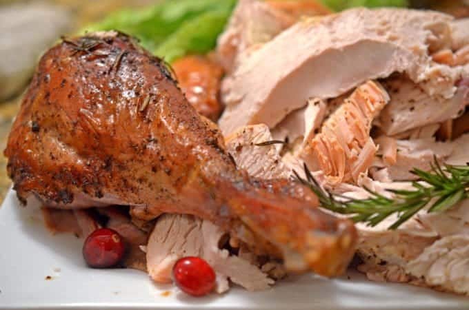 A roasted turkey drumstick on a serving platter with white meat.