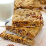 A stack of dessert bars with a glass of milk.