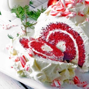 A red velvet cake roll with candy canes on top.