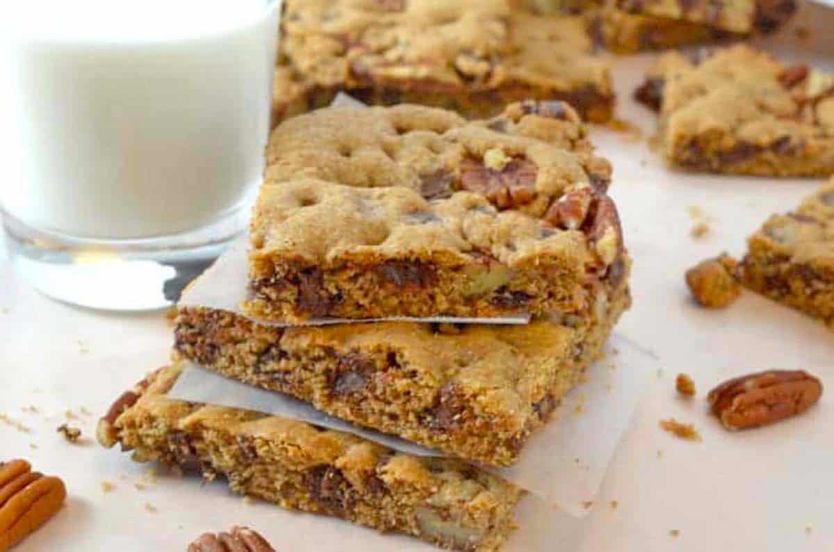 A stack of pecan bars with a glass of milk.