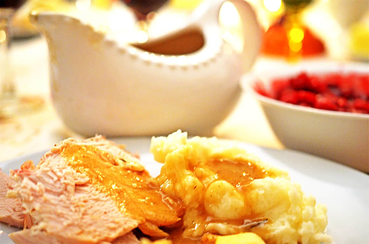 Serving plate of roasted turkey and mashed potatoes, covered with roasted turkey gravy.