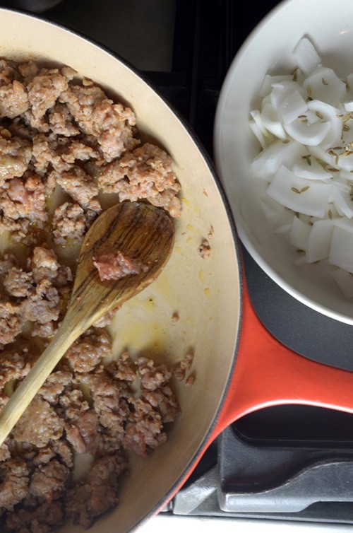 Skillet with browne sausage and onions on the side.