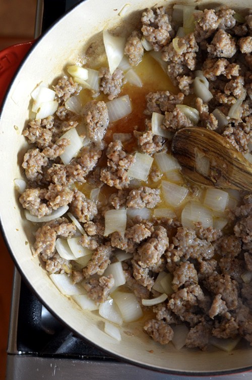 Skllet with browned sausage and onions.