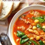 Bowl of white bean soup with sausage and spinach and homemade bread.