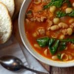 Bowl of white bean and sausage soup with homemade crusty bread.