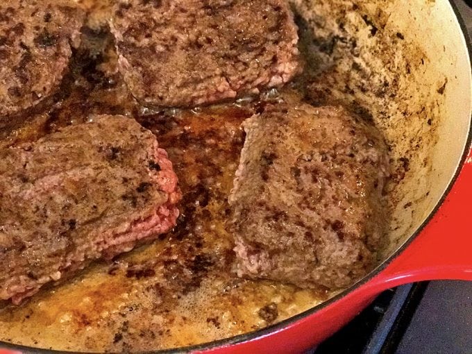 Burgers being fried in skillet 