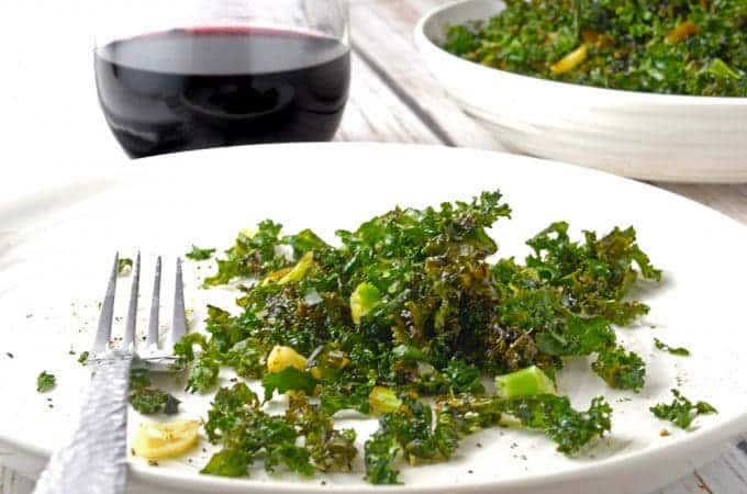 plate of crsipy kale salad with glass of red wine.