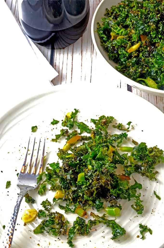 Plate of oven roasted kale with glass of red wine and a fork.