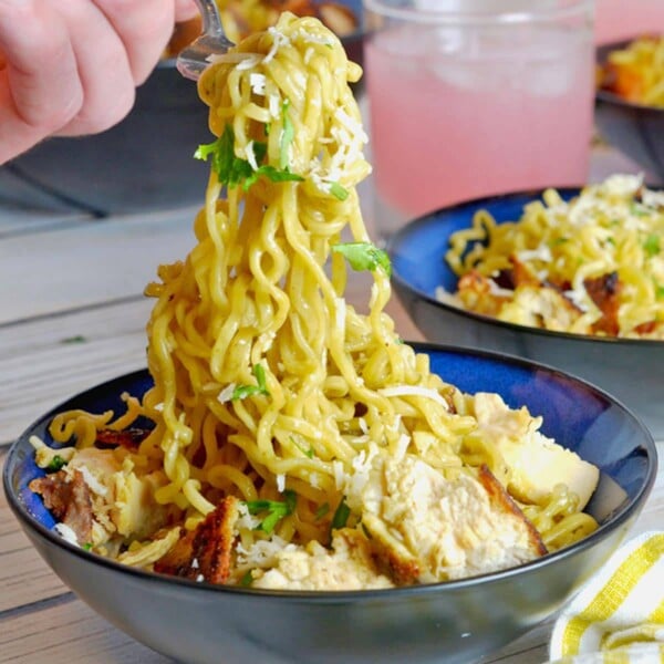 folk pulling up a string of chicken ramen noodles.