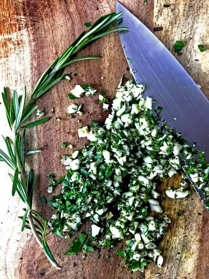 Fresh herbs used for summer chicken succotash with chef's knife.