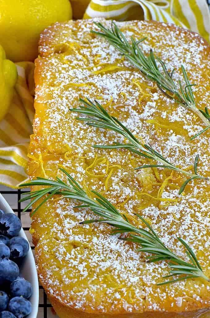 This lemom loaf cake recipe is garnished with sprigs of fresh rosemary.