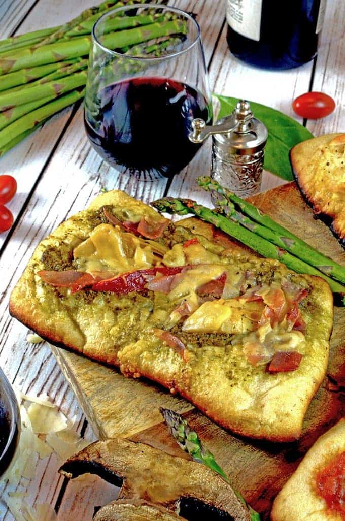 Grilled pizza on a stone on picnic table with asparagus
