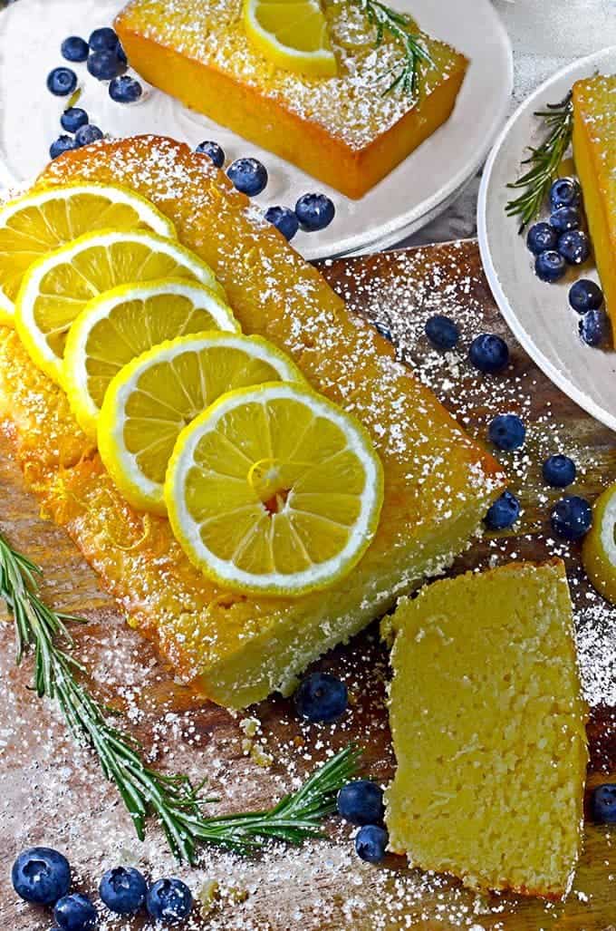 Garnish the lemon loaf cake recipe with fresh lemons, blueberries, and springs of rosemary.