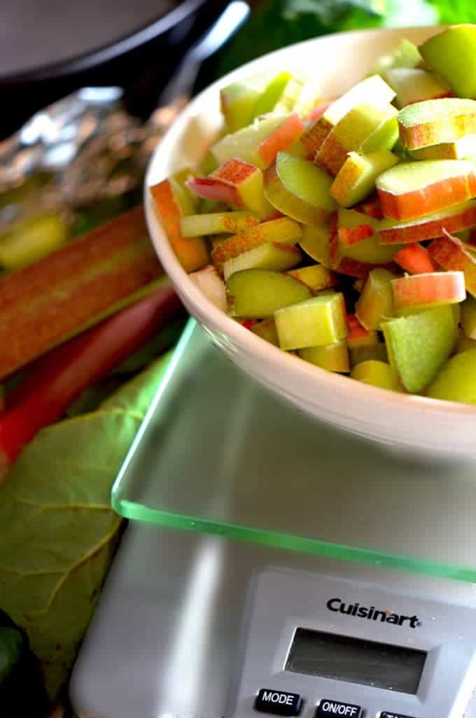 Sliced rhubarb in a dish being weighted on kitchen scale.