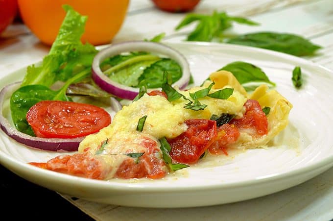 Tomto pie is an easy summer lunch idea. Tomato pie on a plate with fresh tomato salad