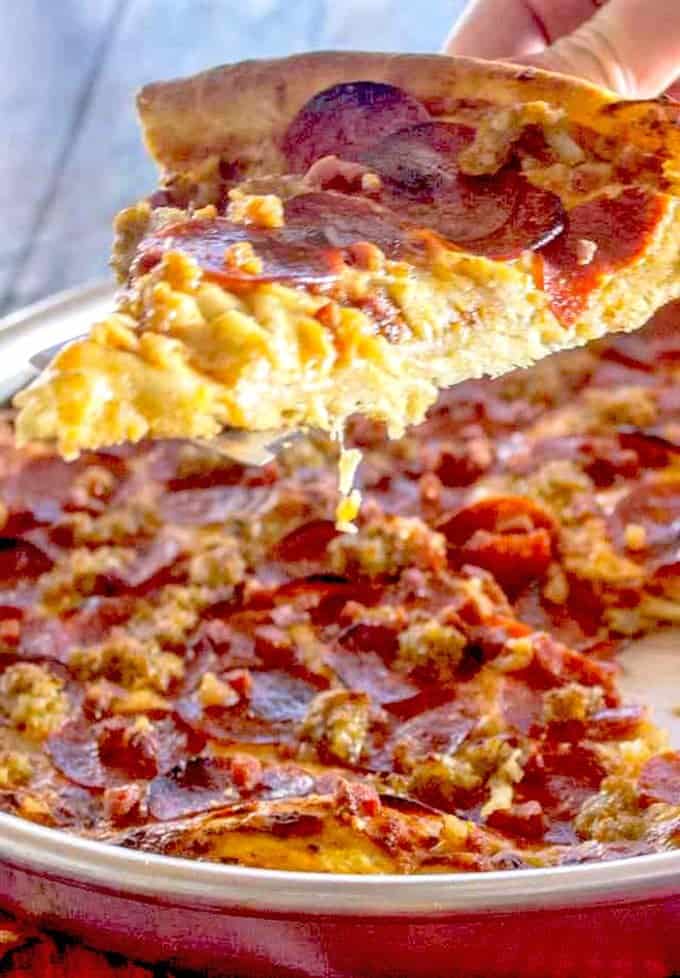 A close up of a slice of pizza being taken from whole pie