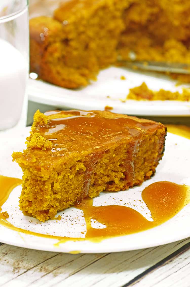 Slice of pumpkin cake with caramel sauce and a glass of milk.