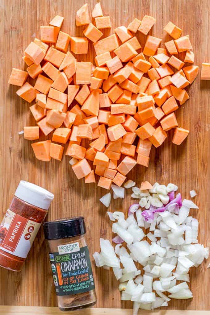 A wooden cutting board with cubes of sweet potato