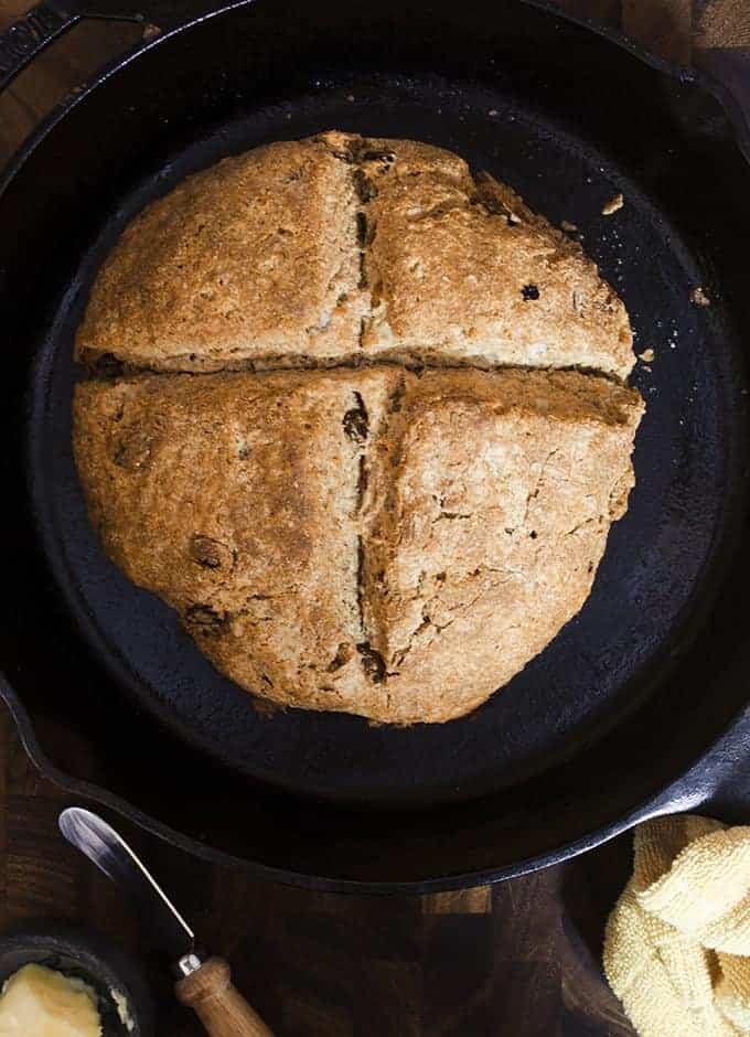 Iron skillet holding baked round of while wheat Irish soda bread