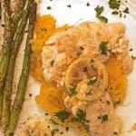 Chicken breast atop shredded squash, asparagus on side with lemon on top