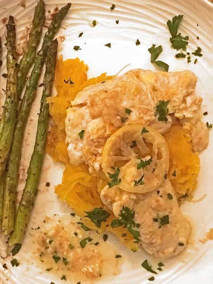 Chicken breast atop shredded squash, asparagus on side with lemon on top