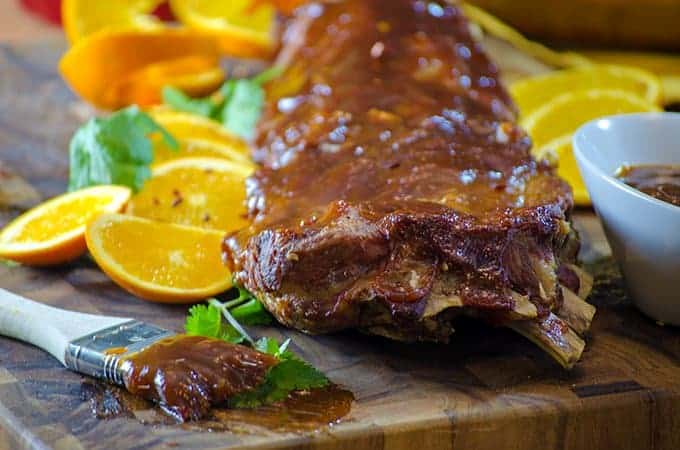 Ribs and sliced oranges on cutting board with parsley