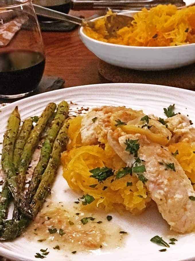 Dinner plate chicken française atop spaghetti squash, asparagus to side