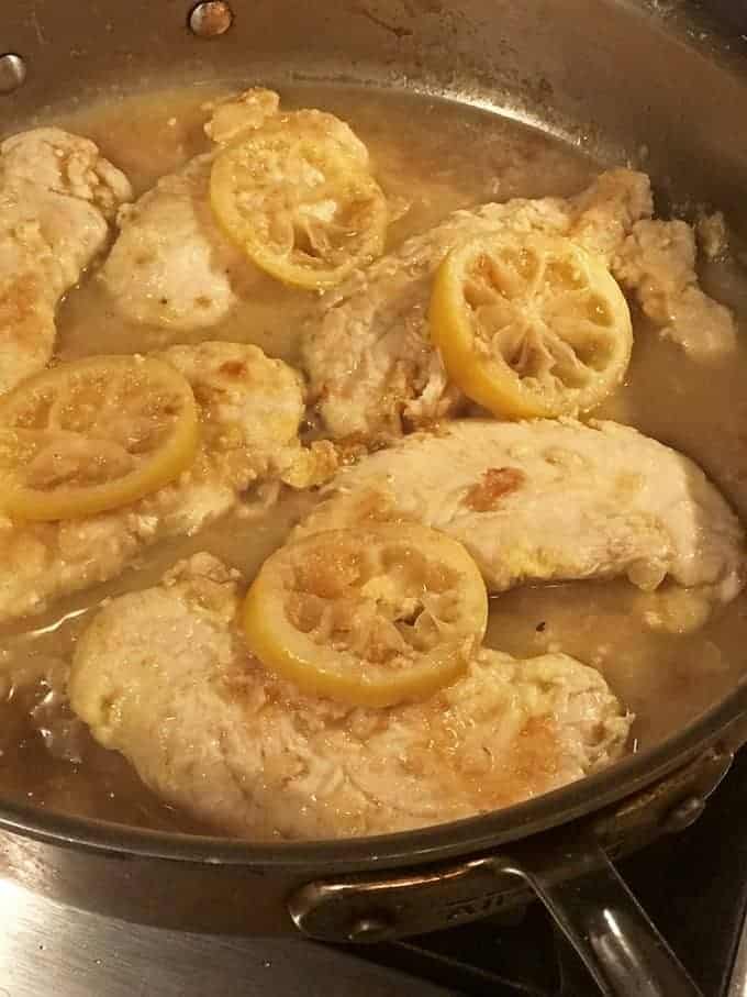 Chicken in pan with sauce and cooked lemon slices