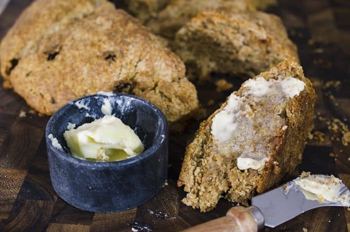 Cut Irish soda bread with buttered slice in foreground, with butter crock and knife
