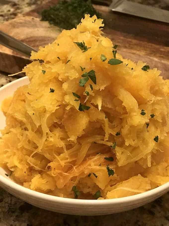 A bowl of spaghetti squash with serving spoon